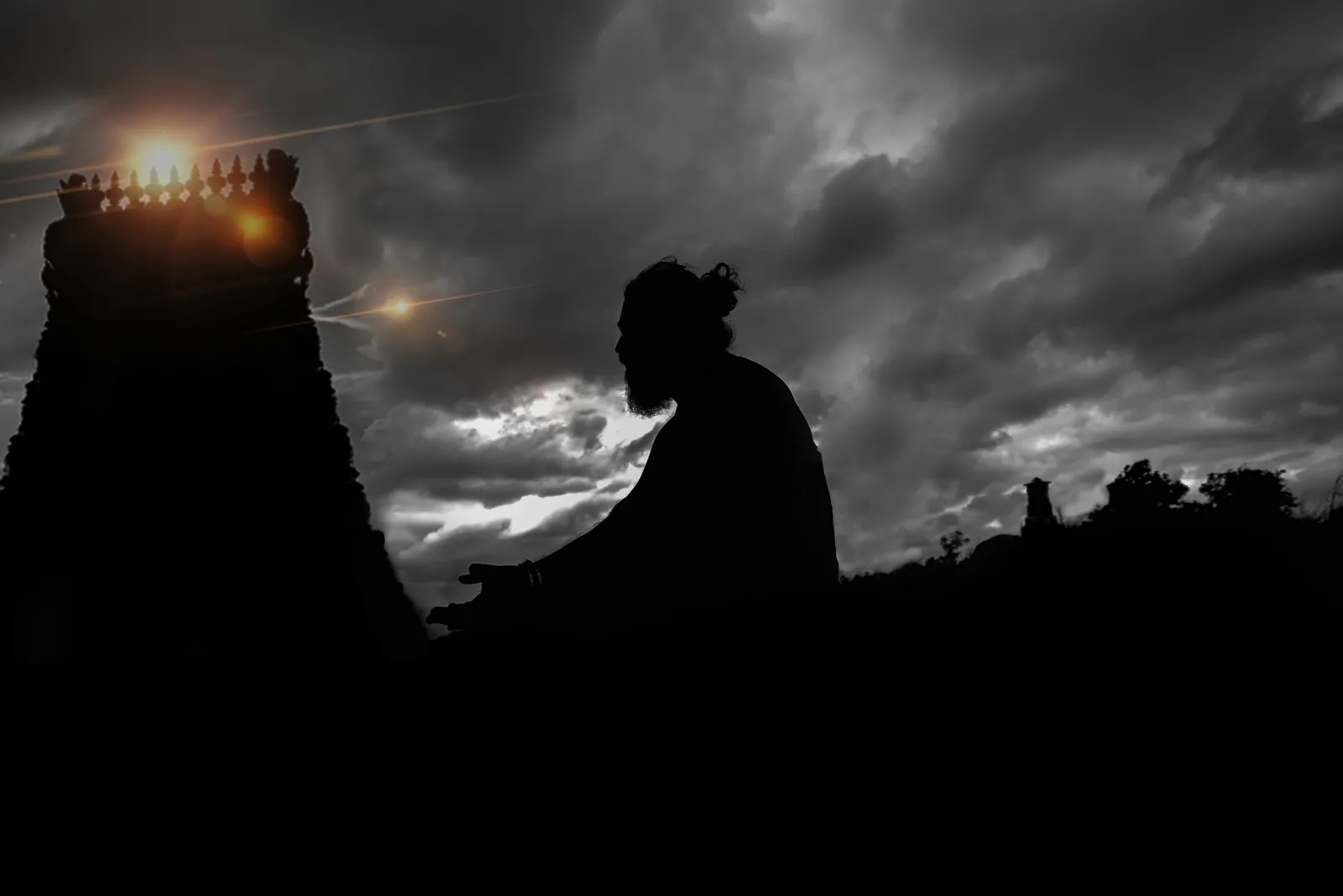 Silhouette of Arun Sharma Guruji in prayer before a temple gopuram at dusk